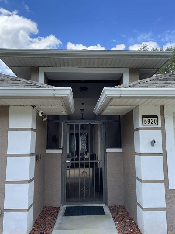 The exterior view shows a house entrance with a metal security door and address numbers — 5920 BAG PIPE PLACE, LEESBURG, FL