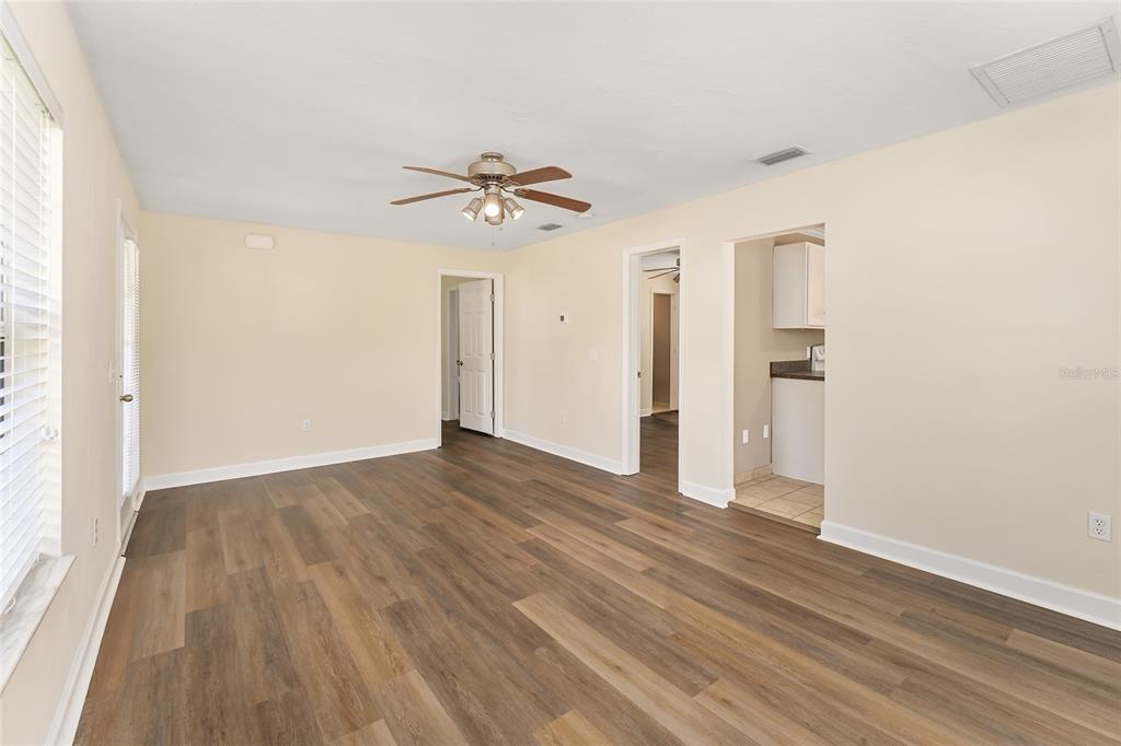 An empty living room features wood-look flooring, a ceiling fan, and doorways leading to other rooms — 18673 NW 252ND STREET, HIGH SPRINGS, FL