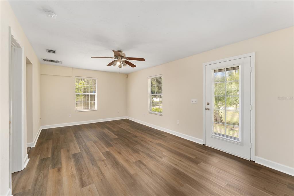 An empty room with wood-look flooring, a ceiling fan, two windows, and a glass door — 18673 NW 252ND STREET, HIGH SPRINGS, FL