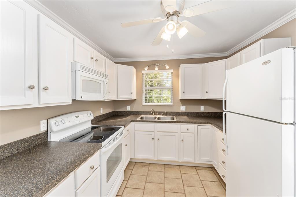 A kitchen with white cabinets, dark countertops, white appliances, and tiled flooring — 18673 NW 252ND STREET, HIGH SPRINGS, FL