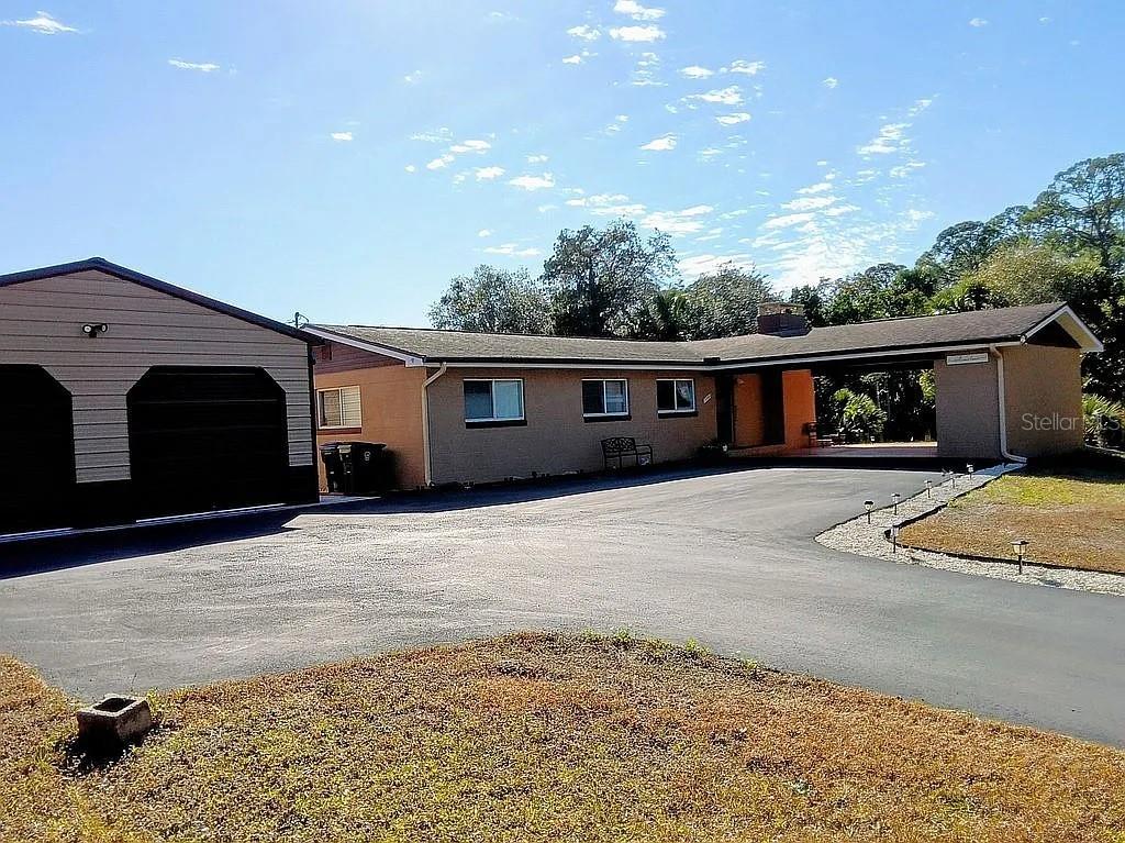 A single-story house with a detached garage and a large paved driveway — 758 BUFFALO ROAD, TITUSVILLE, FL