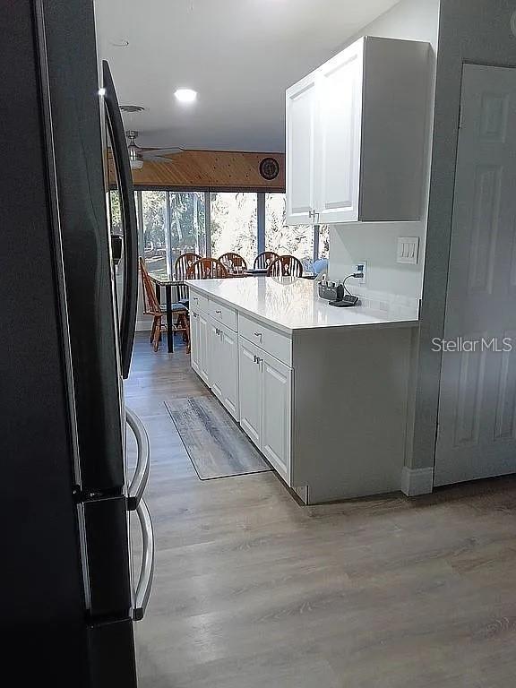 A kitchen features white cabinetry, quartz countertops, and light wood-look flooring — 758 BUFFALO ROAD, TITUSVILLE, FL
