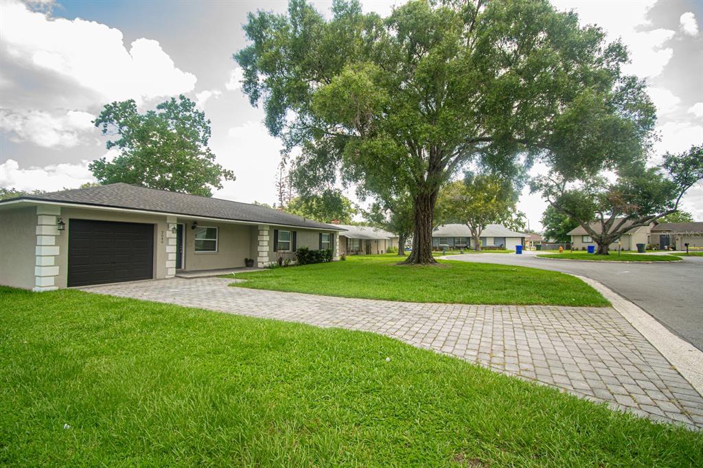 A single-story house with a paved driveway, a dark garage door, and a large front tree — 2040 WOODBRIAR LOOP S, LAKELAND, FL