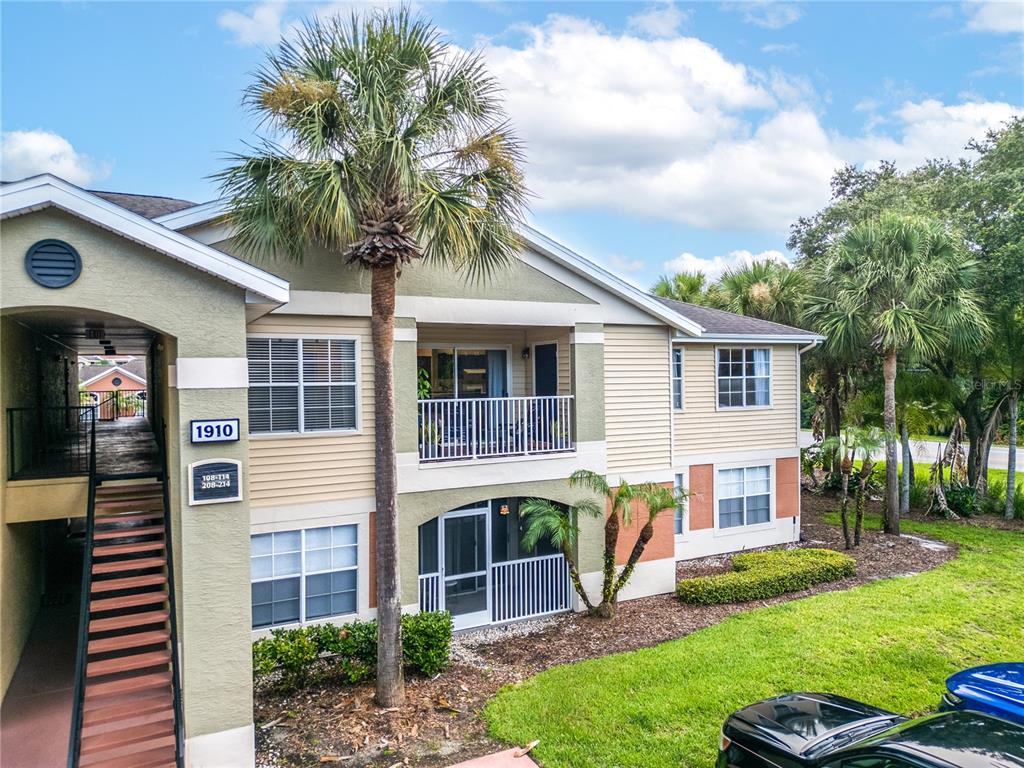 An exterior view of a two-story apartment building with a parking lot in front — 1910 SUMMER CLUB DRIVE UNIT 212, OVIEDO, FL