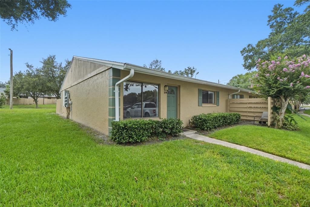 A single-story tan house with a green door, a large window, and a grassy lawn — 220 CHEROKEE COURT UNIT 104, ALTAMONTE SPRINGS, FL