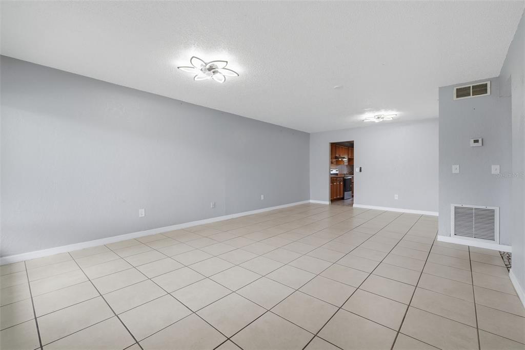 An empty room with light gray walls, tiled flooring, and two modern ceiling light fixtures — 220 CHEROKEE COURT UNIT 104, ALTAMONTE SPRINGS, FL
