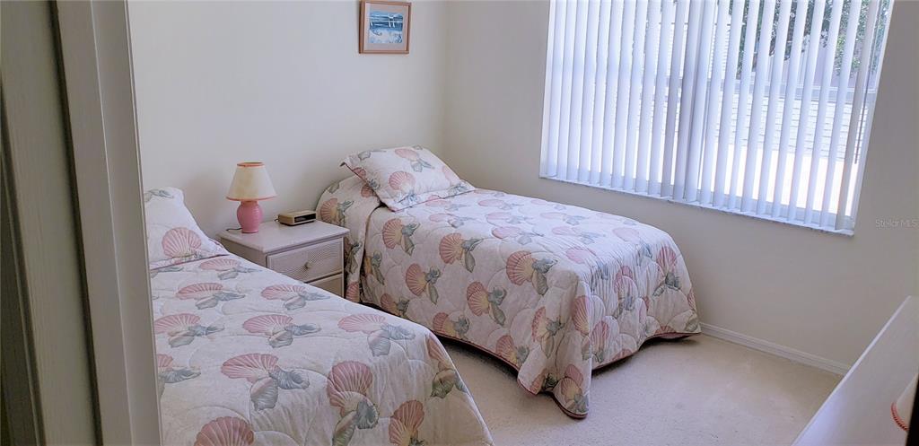 A bedroom features two twin beds with seashell-patterned quilts and a shared nightstand — 5678 SHEFFIELD GREENE CIR UNIT 76, SARASOTA, FL