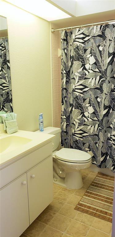 A bathroom features a white vanity, a toilet, and a patterned shower curtain — 5678 SHEFFIELD GREENE CIR UNIT 76, SARASOTA, FL