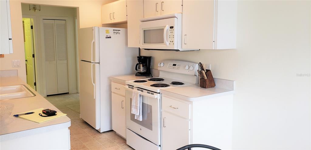 A kitchen features white cabinets, white appliances, and a countertop with a notepad and pen — 5678 SHEFFIELD GREENE CIR UNIT 76, SARASOTA, FL