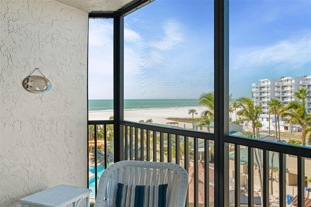 A screened-in balcony overlooks a sandy beach, palm trees, and a multi-story building — 5880 MIDNIGHT PASS ROAD UNIT 605, SARASOTA, FL