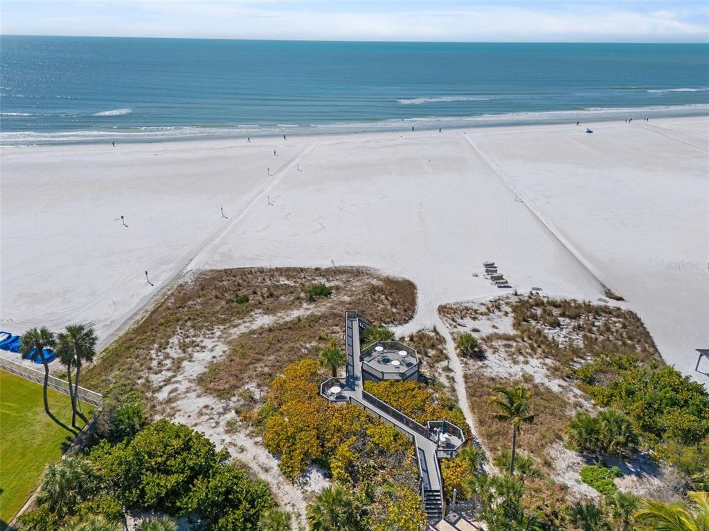An aerial view shows a wooden boardwalk leading to a beach deck overlooking the ocean — 5880 MIDNIGHT PASS ROAD UNIT 605, SARASOTA, FL