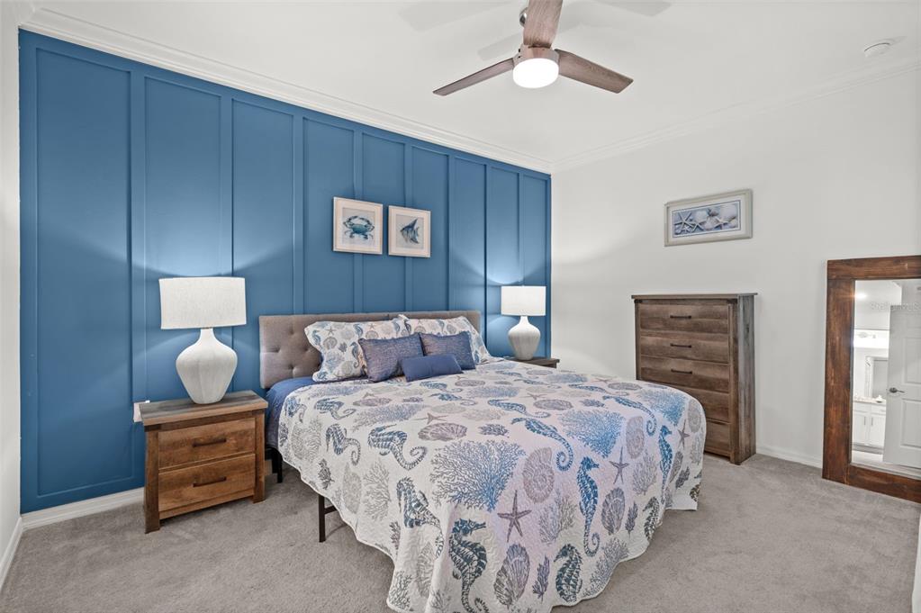 A bedroom features a blue board-and-batten accent wall, a coastal-themed quilt, and wooden furniture — 43040 GREENWAY BOULEVARD UNIT 536, PUNTA GORDA, FL