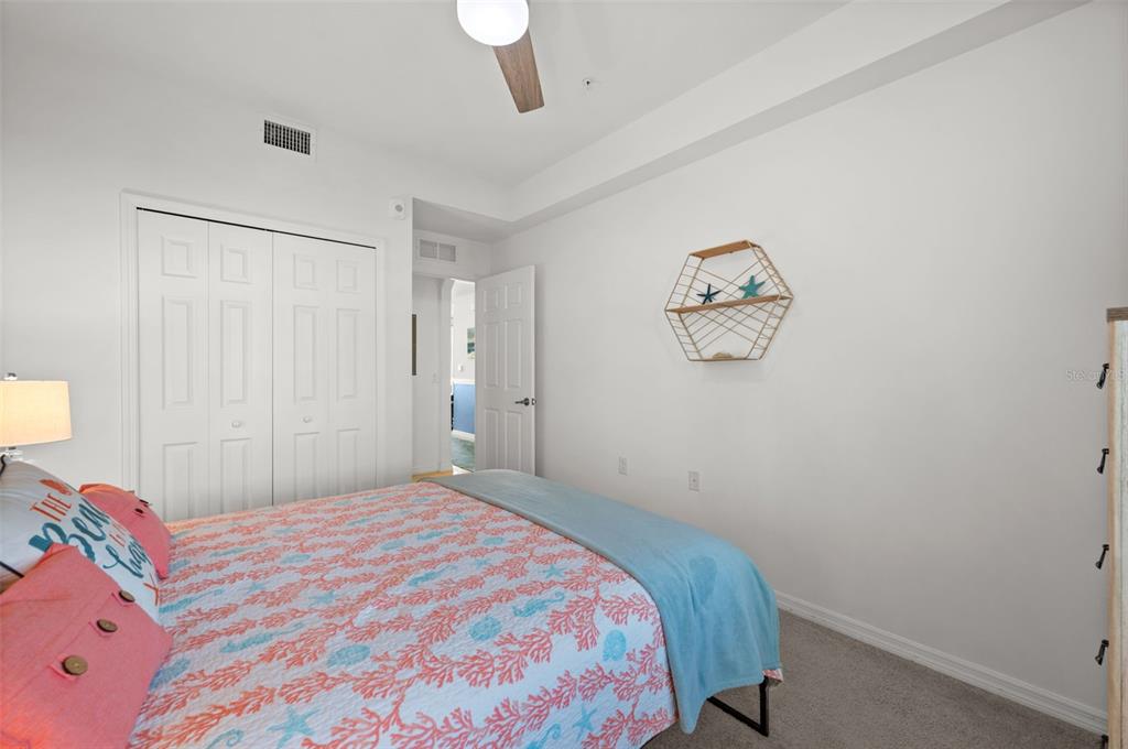 A bedroom features a bed with coral-patterned bedding, a white closet, and a wall shelf — 43040 GREENWAY BOULEVARD UNIT 536, PUNTA GORDA, FL