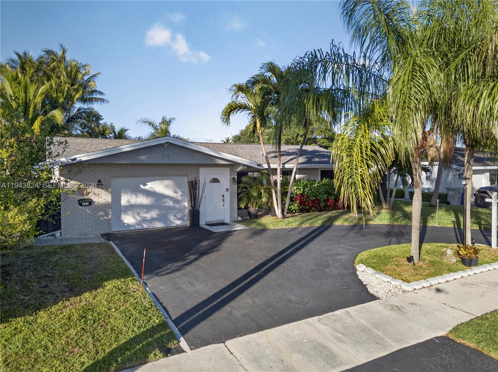 A single-story house with a brick facade, a white garage door, and a paved driveway — 371 SE 3rd St, Pompano Beach FL 33060, POMPANO BEACH, FL