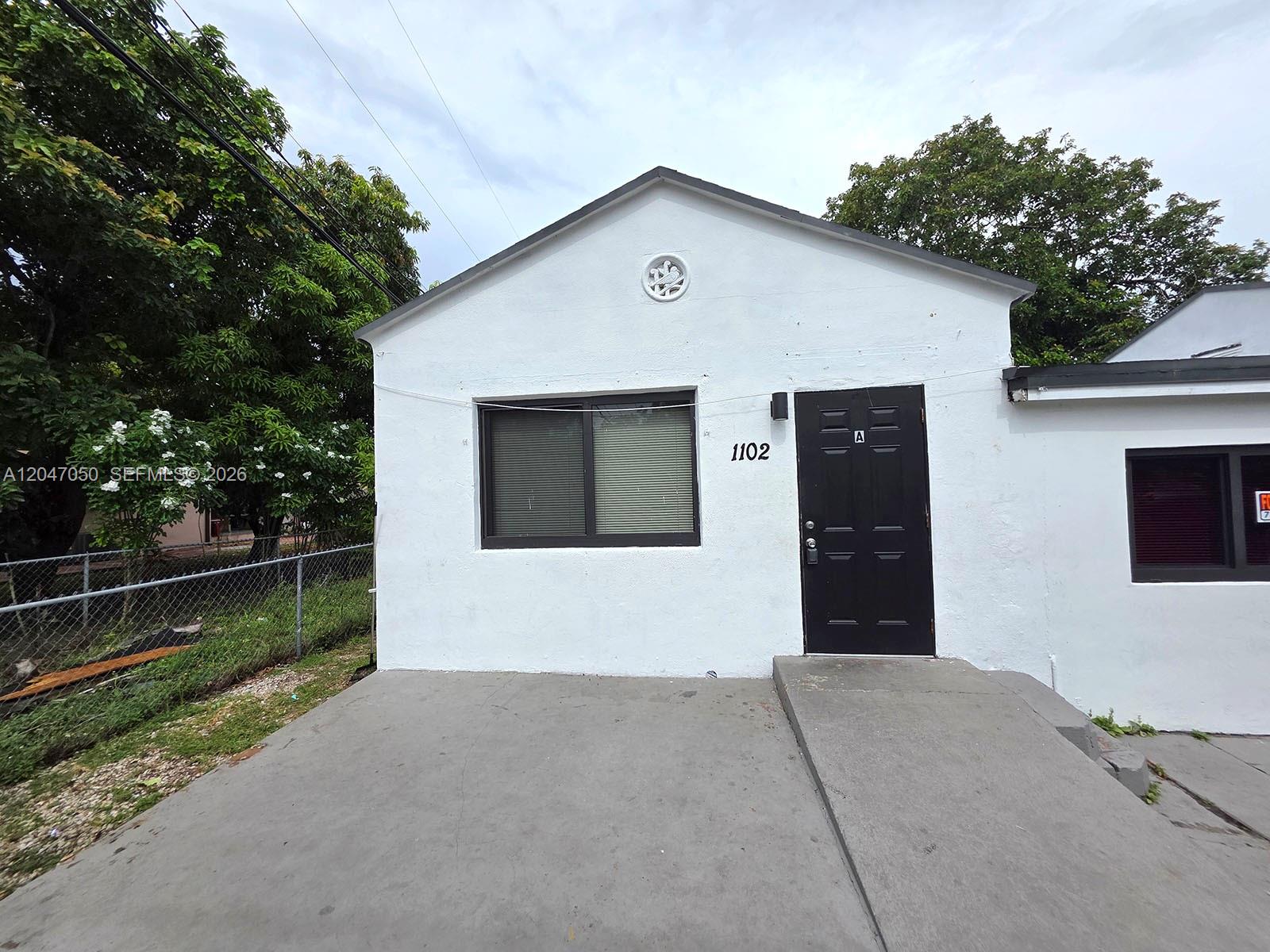 A white single-story building features a black door, a window, and a concrete entrance ramp — 1102 NW 103rd St, Miami FL 33150, MIAMI, FL