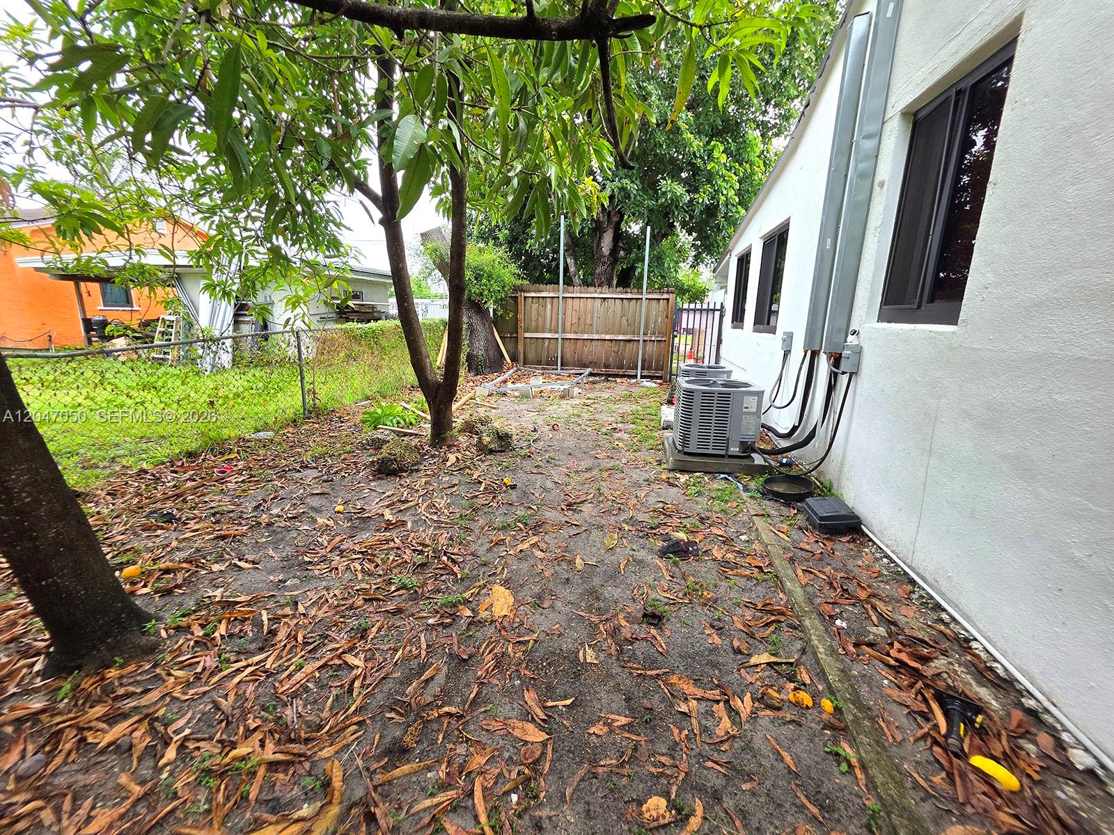 A backyard area features a white house exterior, two air conditioning units, and a wooden fence — 1102 NW 103rd St, Miami FL 33150, MIAMI, FL