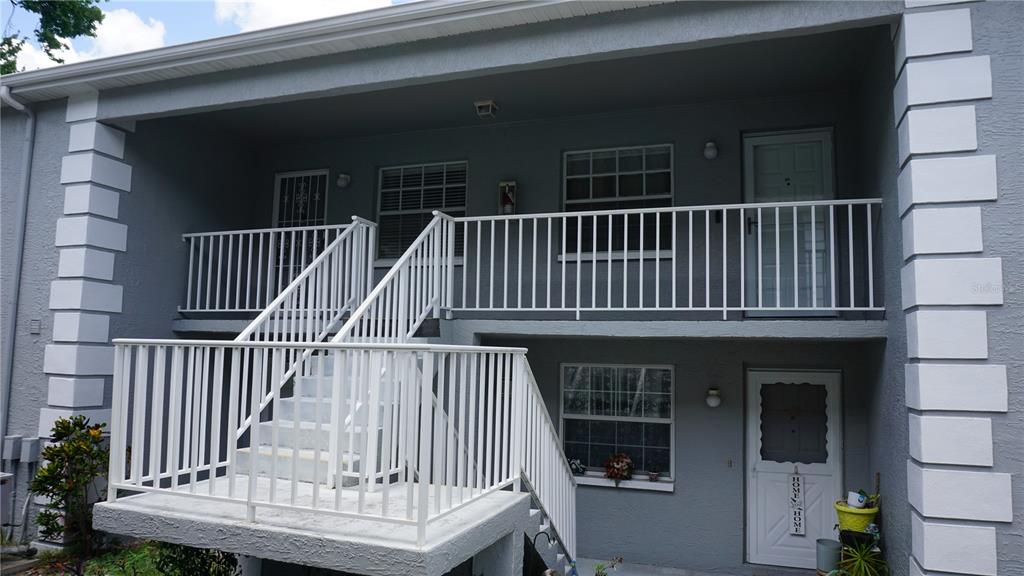 An exterior view of a two-story apartment building with white railings and a staircase — 12141 SPARTAN WAY UNIT 204, HUDSON, FL