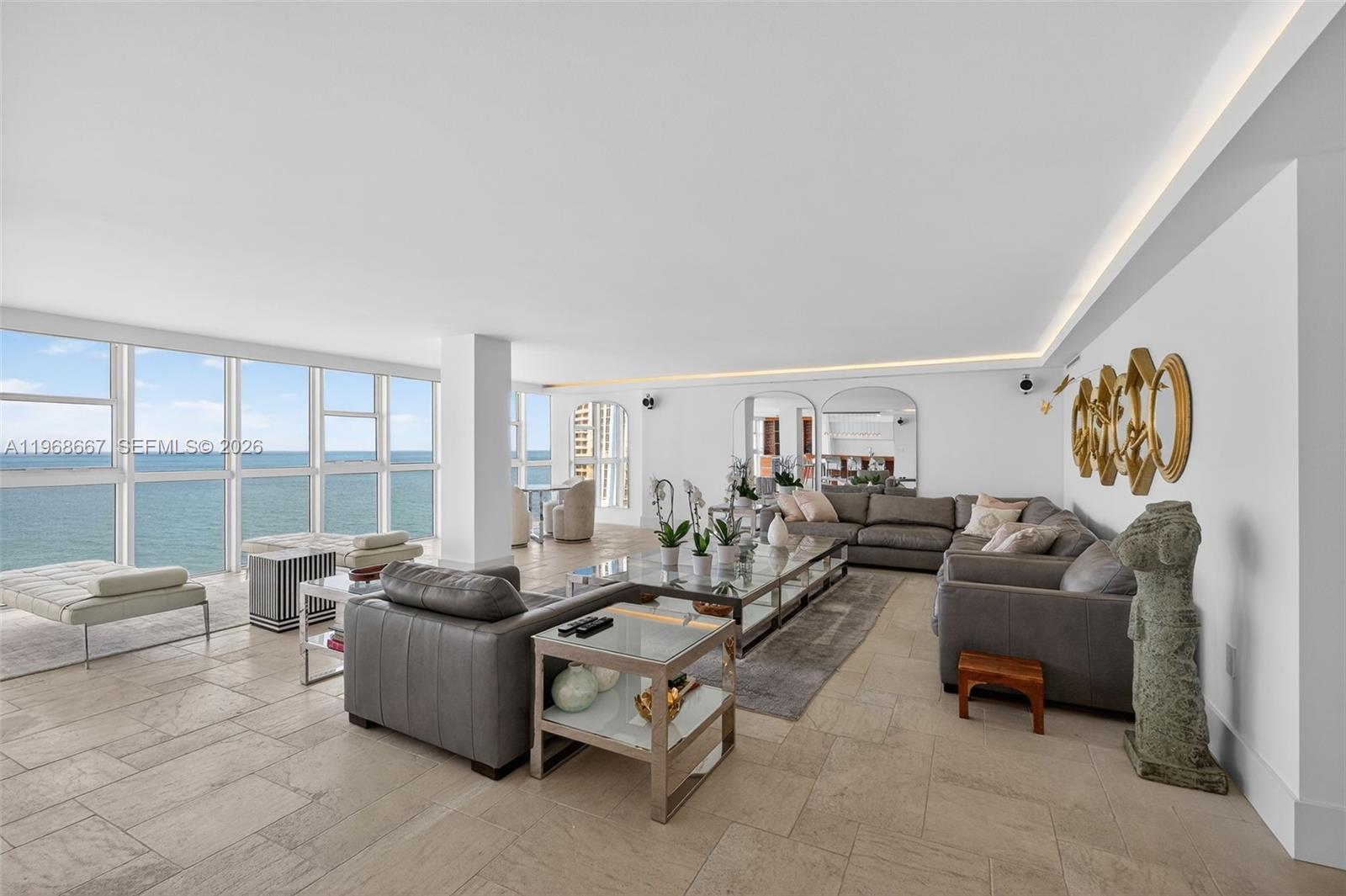 A spacious living room features gray leather sofas, a glass coffee table, and ocean views — 600 Grapetree Dr, Key Biscayne FL 33149, KEY BISCAYNE, FL