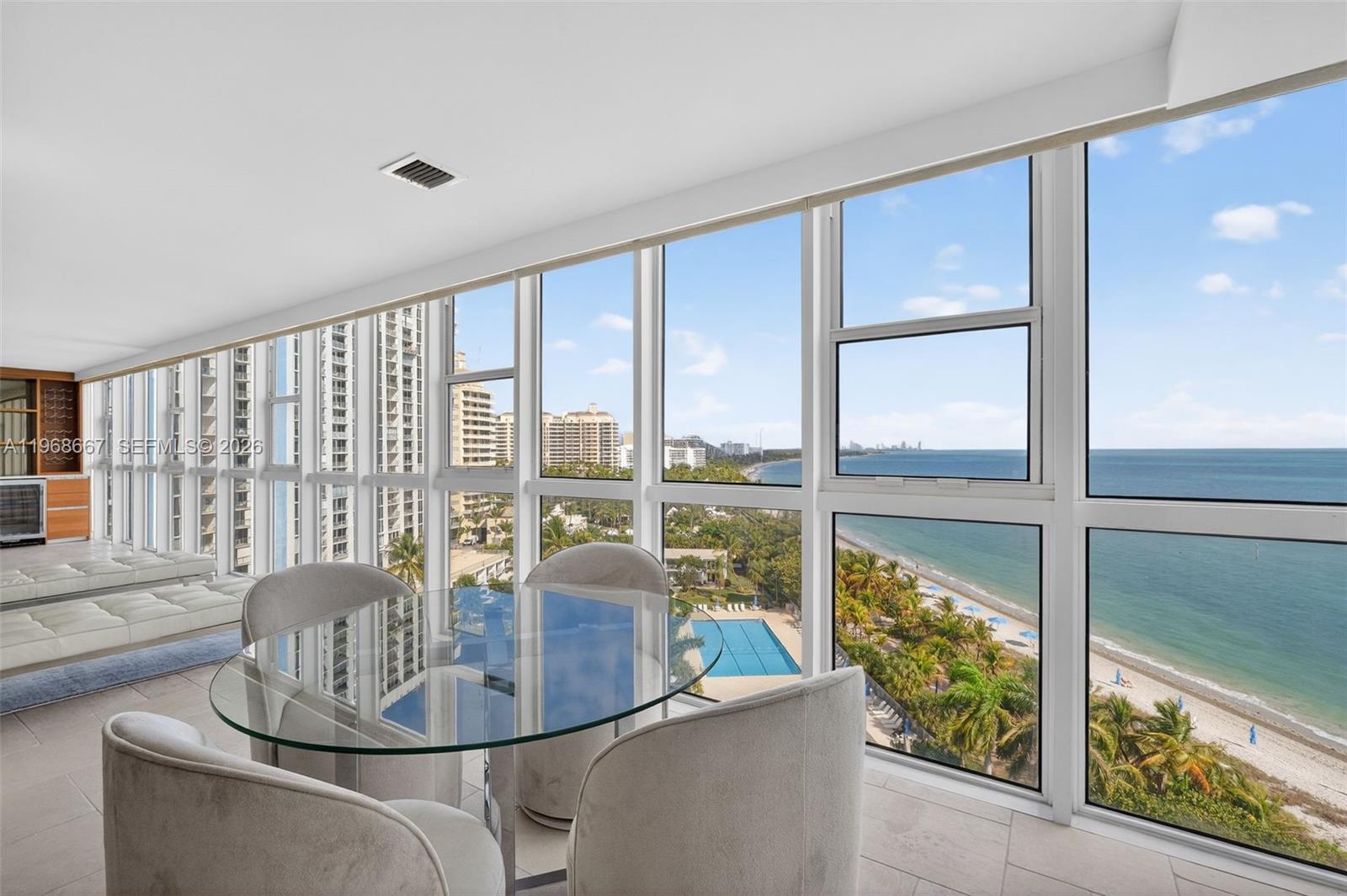 A dining area with a glass table overlooks a beach, ocean, and swimming pool — 600 Grapetree Dr, Key Biscayne FL 33149, KEY BISCAYNE, FL