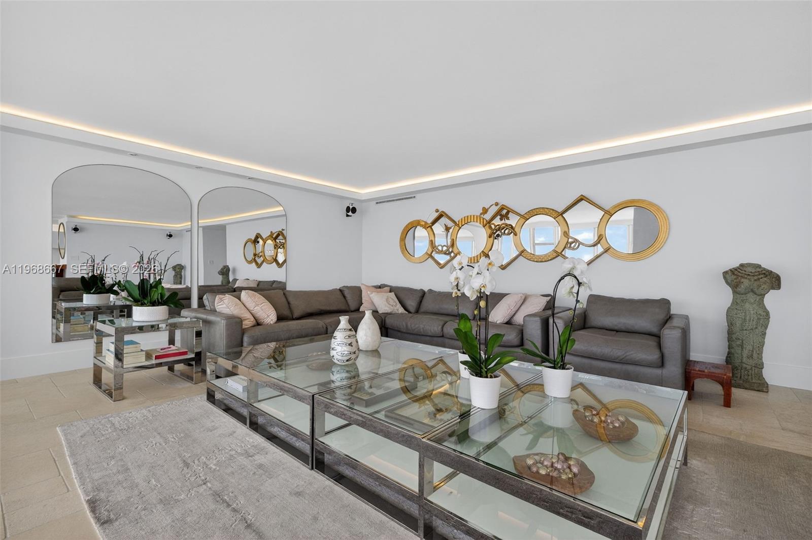 A living room features a large grey sectional sofa, glass coffee tables, and decorative wall mirrors — 600 Grapetree Dr, Key Biscayne FL 33149, KEY BISCAYNE, FL