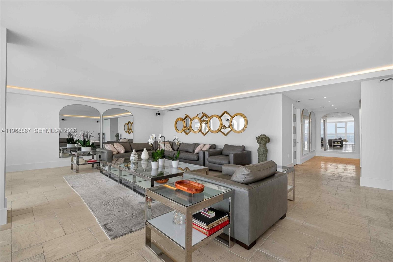 A modern living room features gray leather sofas, glass coffee tables, and arched wall mirrors — 600 Grapetree Dr, Key Biscayne FL 33149, KEY BISCAYNE, FL