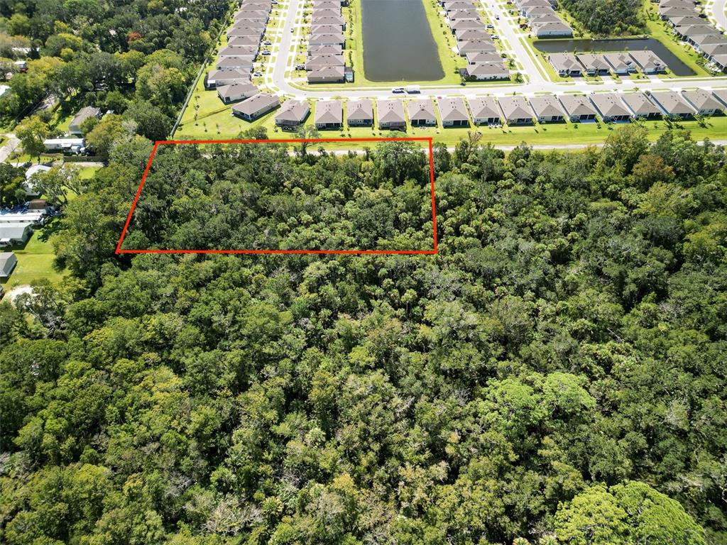 An aerial view shows a rectangular plot of land outlined in red amidst dense forest — 1521 OCUAN TRAIL, NEW SMYRNA BEACH, FL