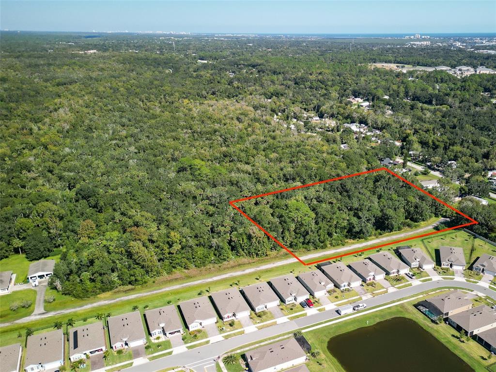 An aerial view shows a rectangular plot of land outlined in red near a residential neighborhood — 1521 OCUAN TRAIL, NEW SMYRNA BEACH, FL