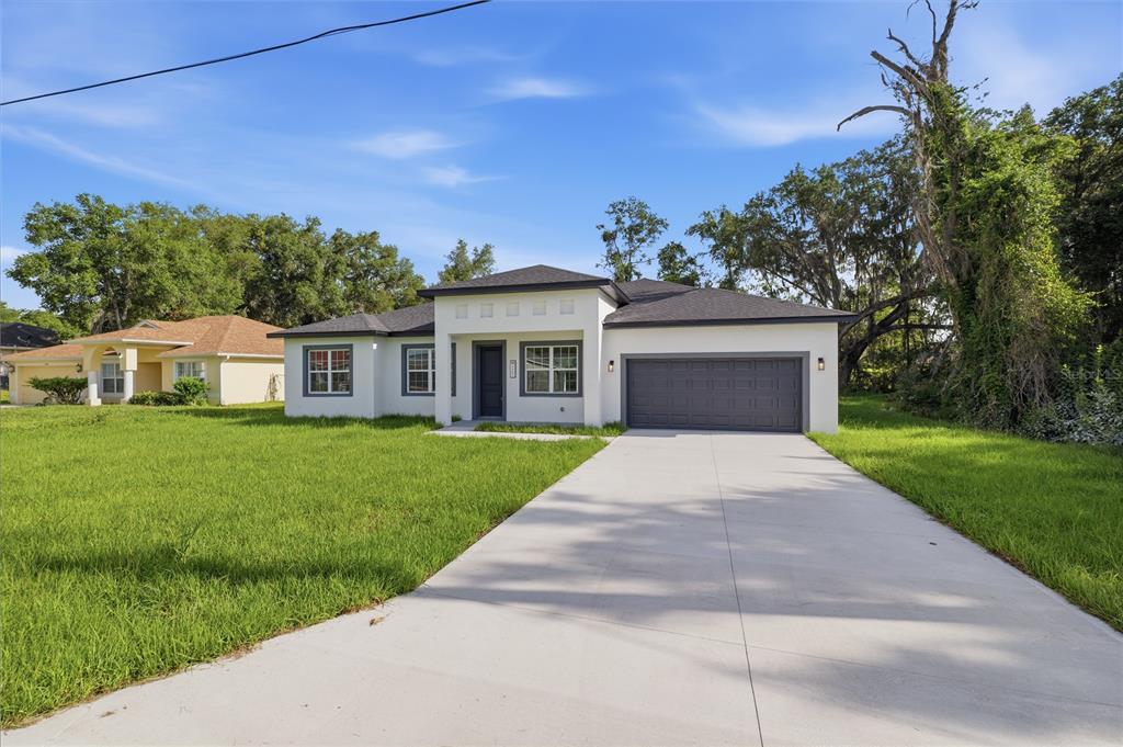 A modern, white single-story house with a gray garage and a concrete driveway — 4465 SW 132ND STREET, OCALA, FL