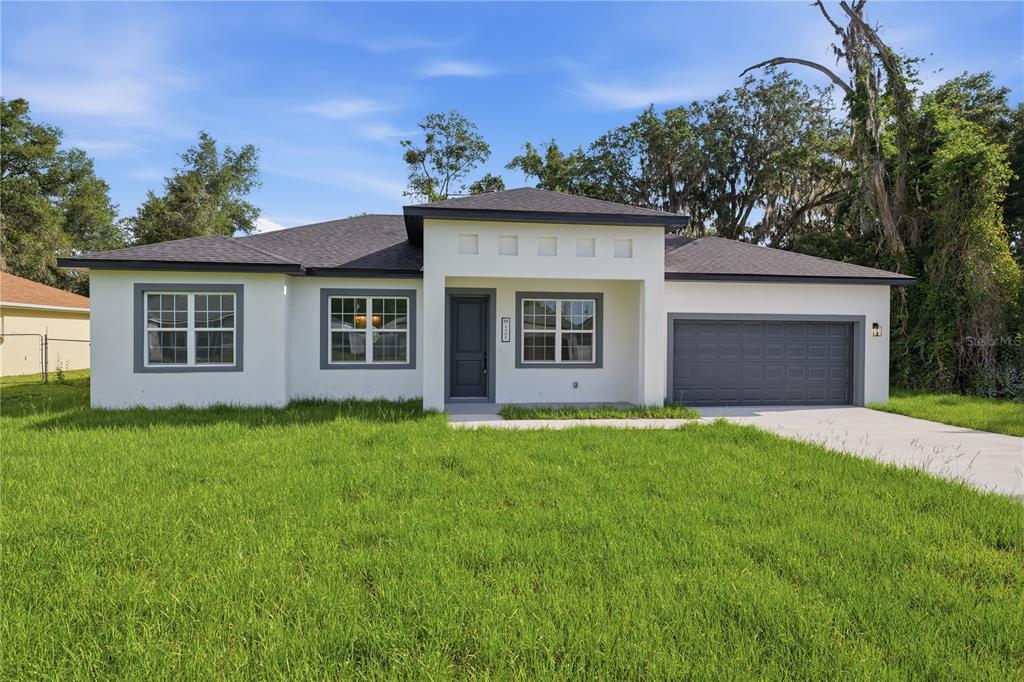 A single-story house with white stucco walls, gray trim, and an attached two-car garage — 4465 SW 132ND STREET, OCALA, FL