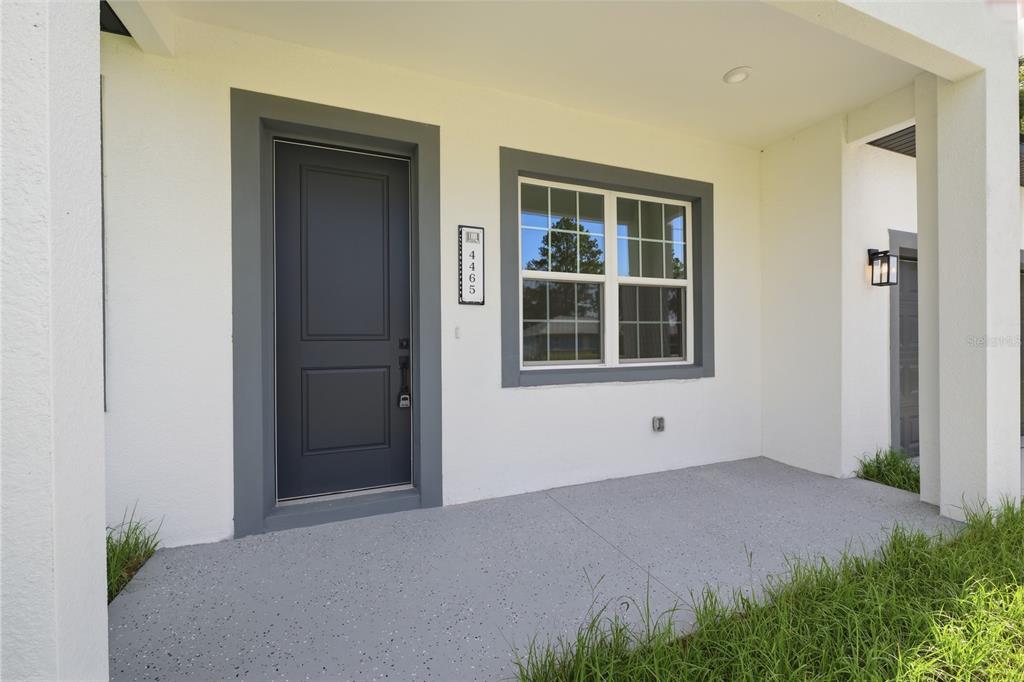 A covered concrete front porch features a dark gray door and a matching window frame — 4465 SW 132ND STREET, OCALA, FL