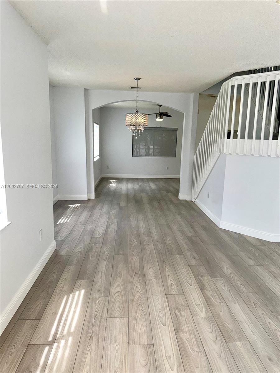 An interior view shows a living area with light wood-look flooring and a staircase railing — 1704 SW 101st Ter, Miramar FL 33025, MIRAMAR, FL