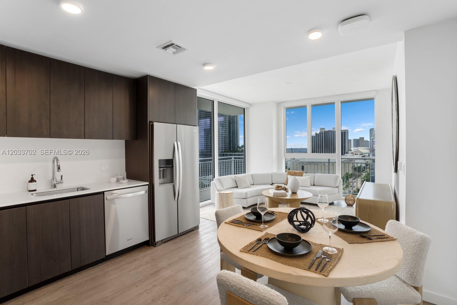 A modern kitchen and dining area feature dark wood cabinets, stainless appliances, and city views — 2000 Biscayne Blvd # 1707, Miami FL 33137, MIAMI, FL