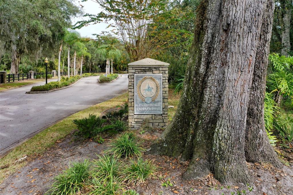 A stone monument sign for the Flagler Beach Polo Club stands beside a paved road — 105 BRIDLE RIDGE COURT, FLAGLER BEACH, FL