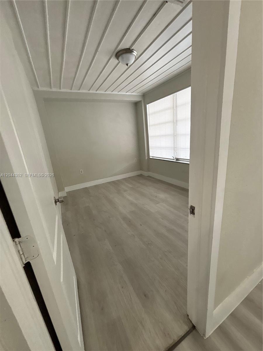 An empty room features light-colored wood-look flooring, neutral walls, and a white paneled ceiling — 5011 SW 5th St # 0, Miami FL 33134, MIAMI, FL