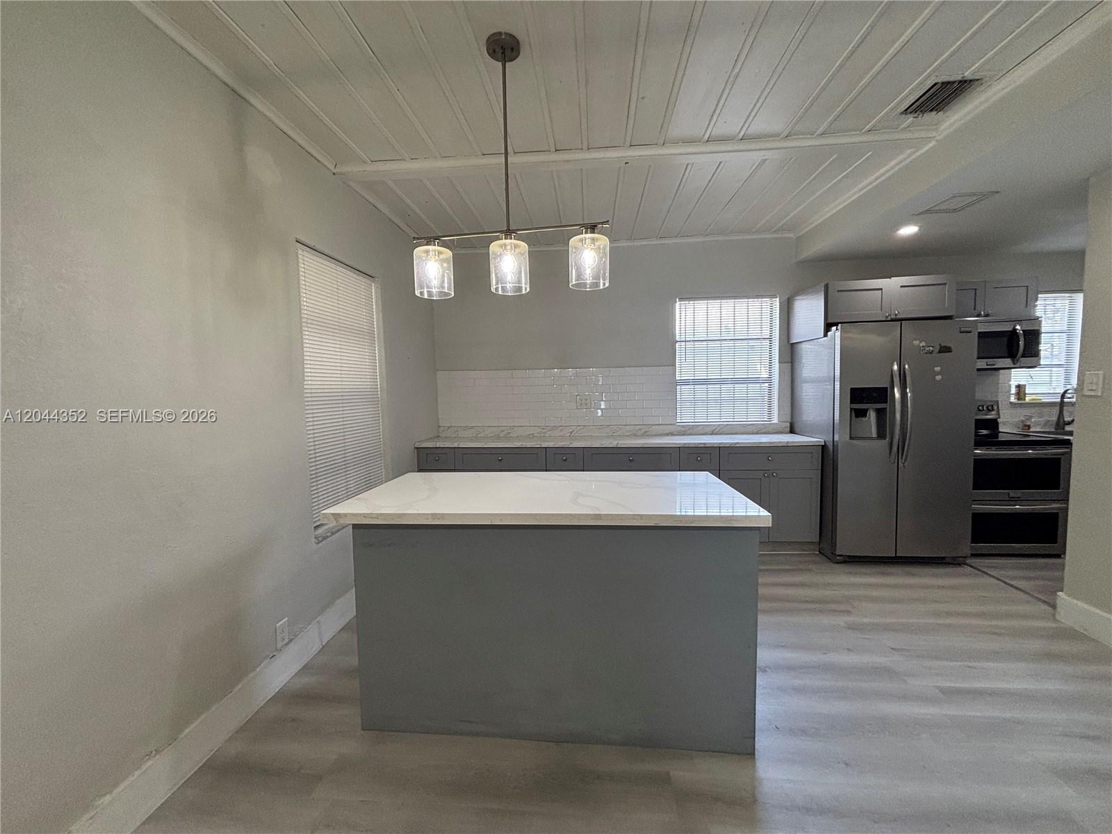A kitchen features a gray island, stainless steel appliances, and a white plank ceiling — 5011 SW 5th St # 0, Miami FL 33134, MIAMI, FL