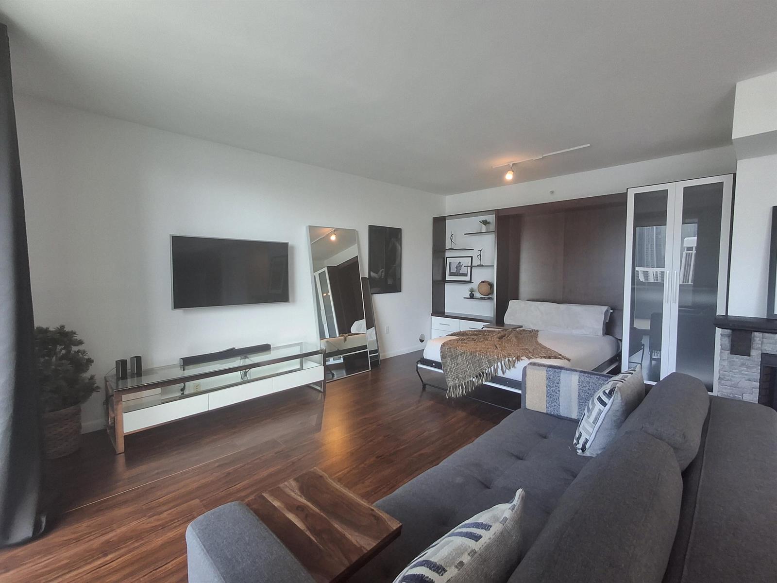 A studio apartment features a wall bed, a grey sofa, and a glass media console — 244 Biscayne Boulevard # 2805, Miami FL 33132, MIAMI, FL
