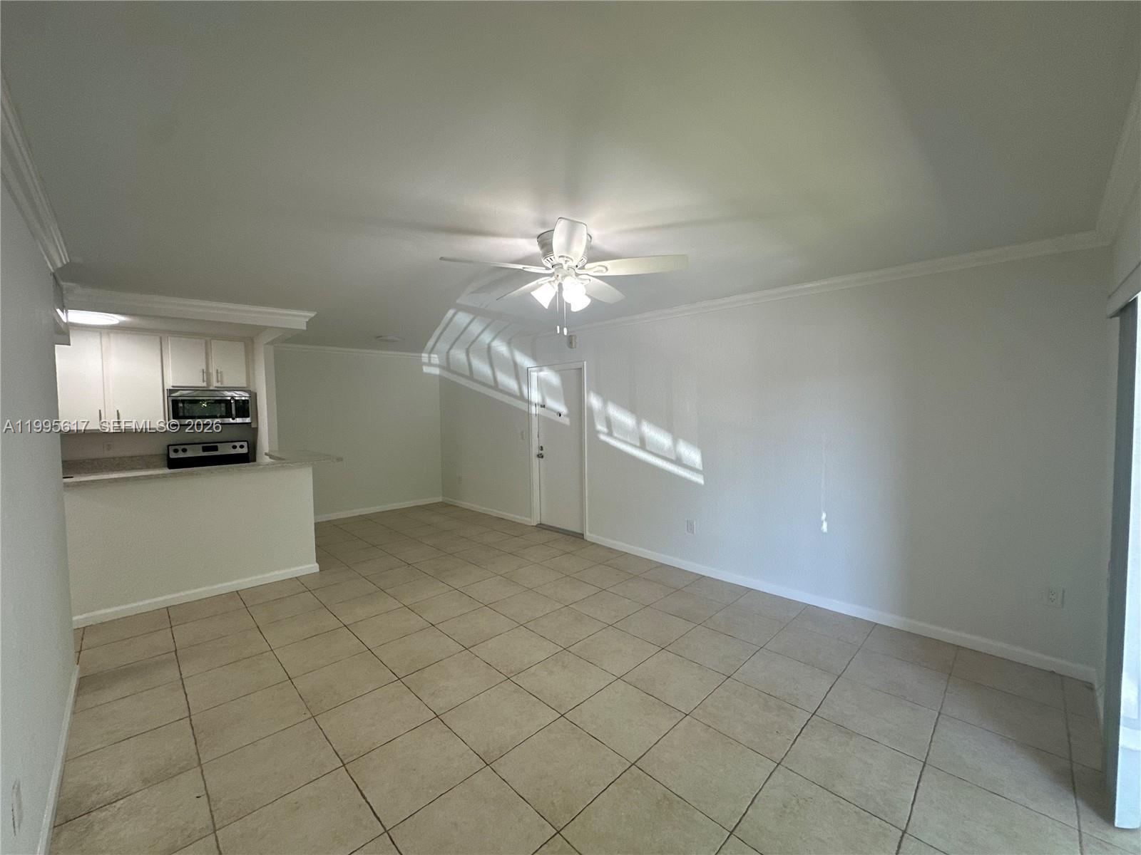 An open-concept living area features light tile flooring, a ceiling fan, and a small kitchen — 7951 SW 104th St # 209D, Miami FL 33156, MIAMI, FL
