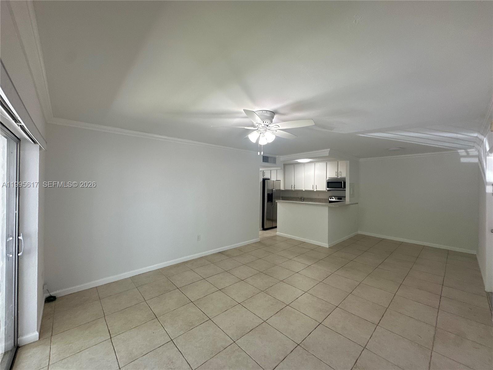 An open-concept living area features light-colored tile flooring, white walls, and a kitchen with white cabinetry — 7951 SW 104th St # 209D, Miami FL 33156, MIAMI, FL
