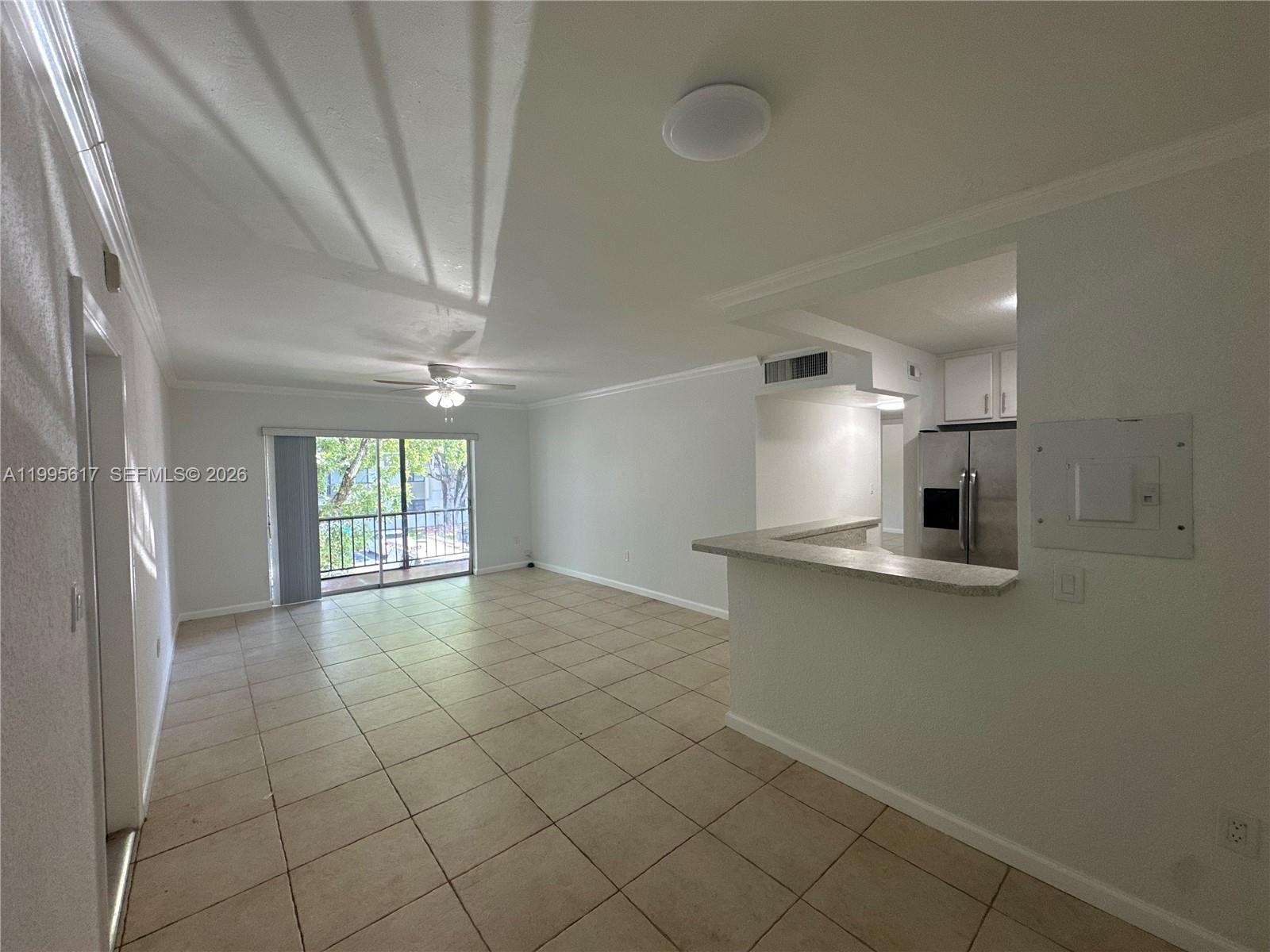 An open-concept living area features tile flooring, a breakfast bar, and a sliding glass door — 7951 SW 104th St # 209D, Miami FL 33156, MIAMI, FL