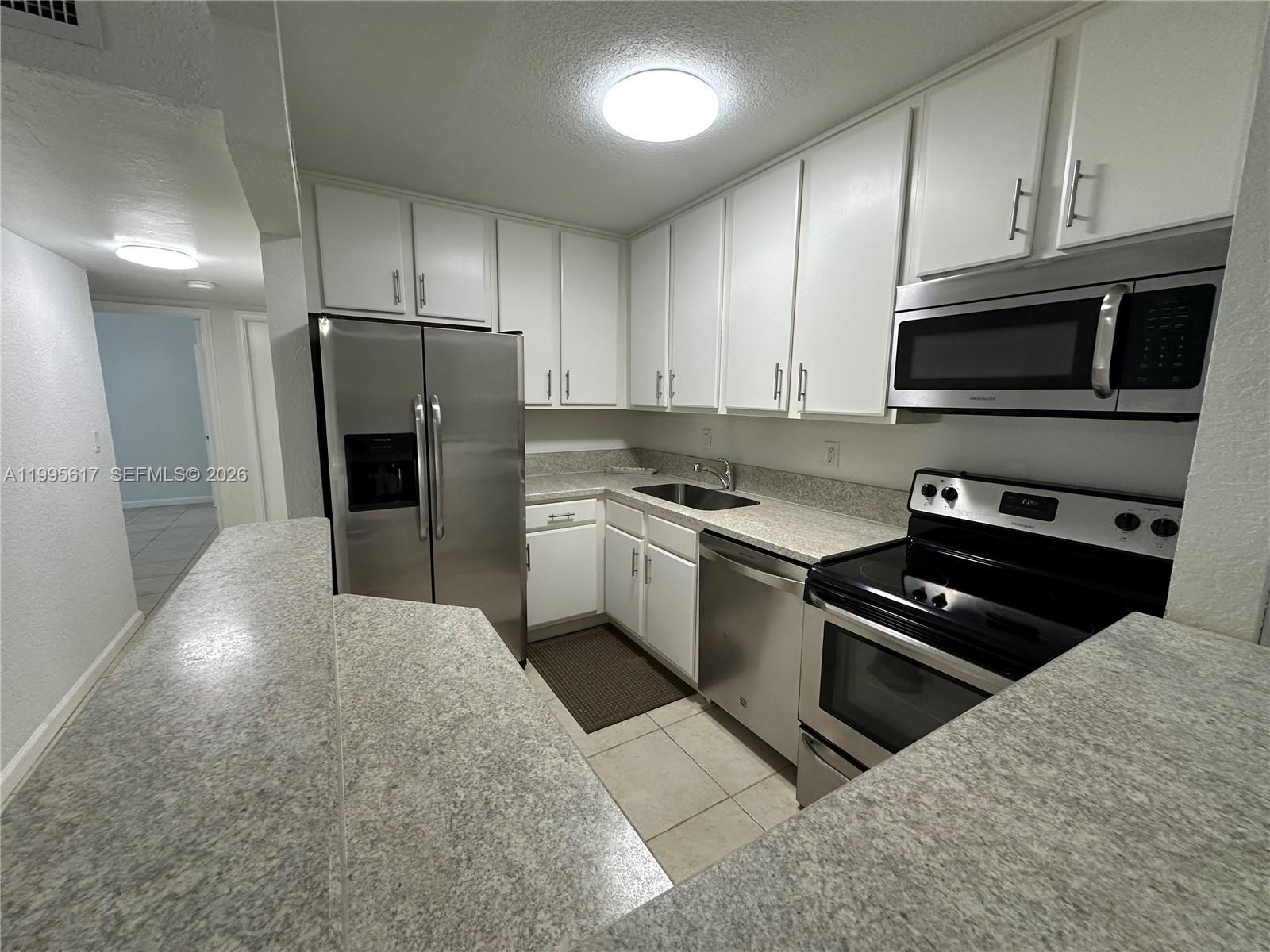A kitchen features white cabinets, stainless steel appliances, and speckled laminate countertops — 7951 SW 104th St # 209D, Miami FL 33156, MIAMI, FL