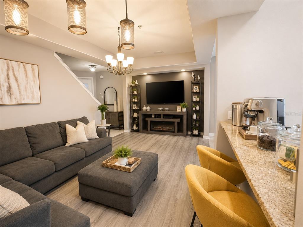 A living room features a grey sectional, a matching ottoman, and a breakfast bar area — 4903 MATTEO TRAIL, ORLANDO, FL