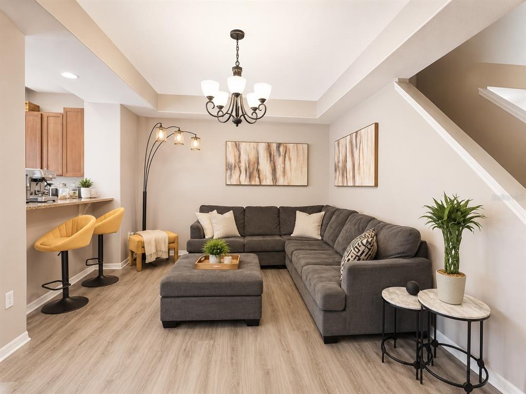 A living room features a gray sectional sofa, a matching ottoman, and a breakfast bar — 4903 MATTEO TRAIL, ORLANDO, FL