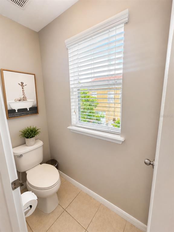 A small bathroom features a toilet, a window with white blinds, and giraffe wall art — 4903 MATTEO TRAIL, ORLANDO, FL