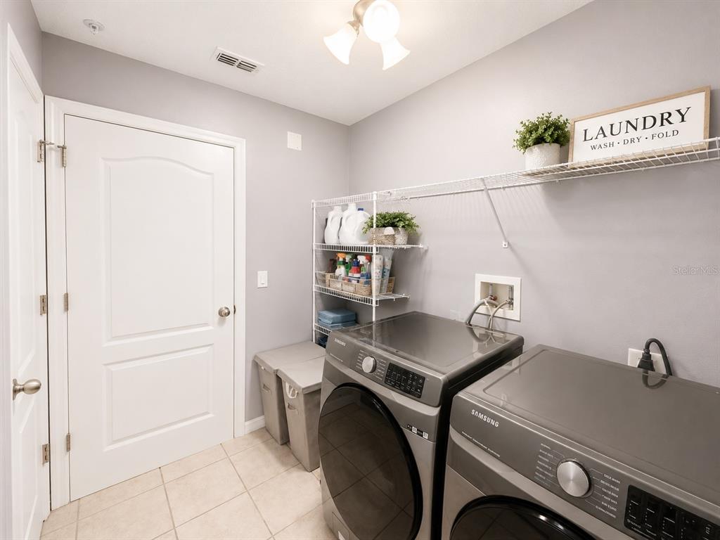 A laundry room features grey walls, tile flooring, Samsung appliances, and wire shelving — 4903 MATTEO TRAIL, ORLANDO, FL