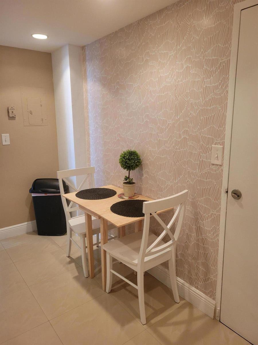 A small dining area features a wooden table, two white chairs, and patterned wallpaper — 3901 S Ocean Drive # 12t, Hollywood FL 33019, HOLLYWOOD, FL
