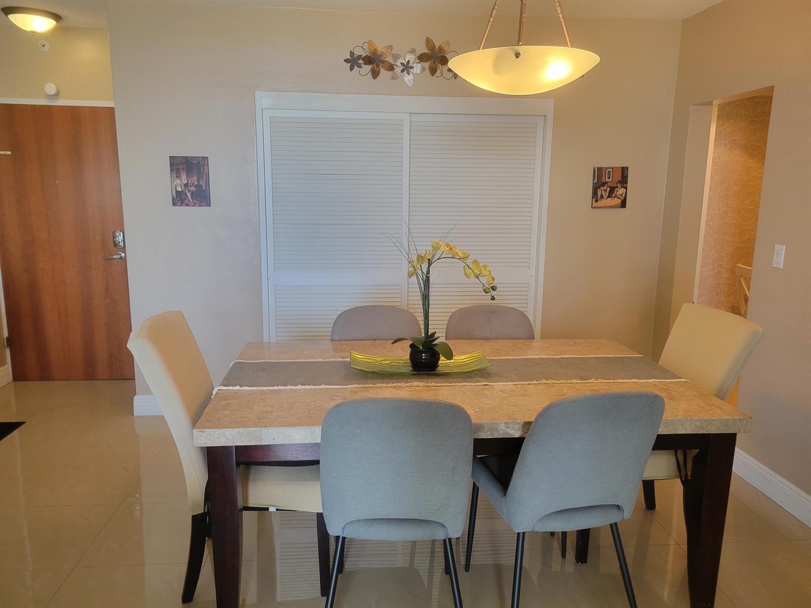 A dining room features a stone-topped table, six chairs, and a modern pendant light — 3901 S Ocean Drive # 12t, Hollywood FL 33019, HOLLYWOOD, FL