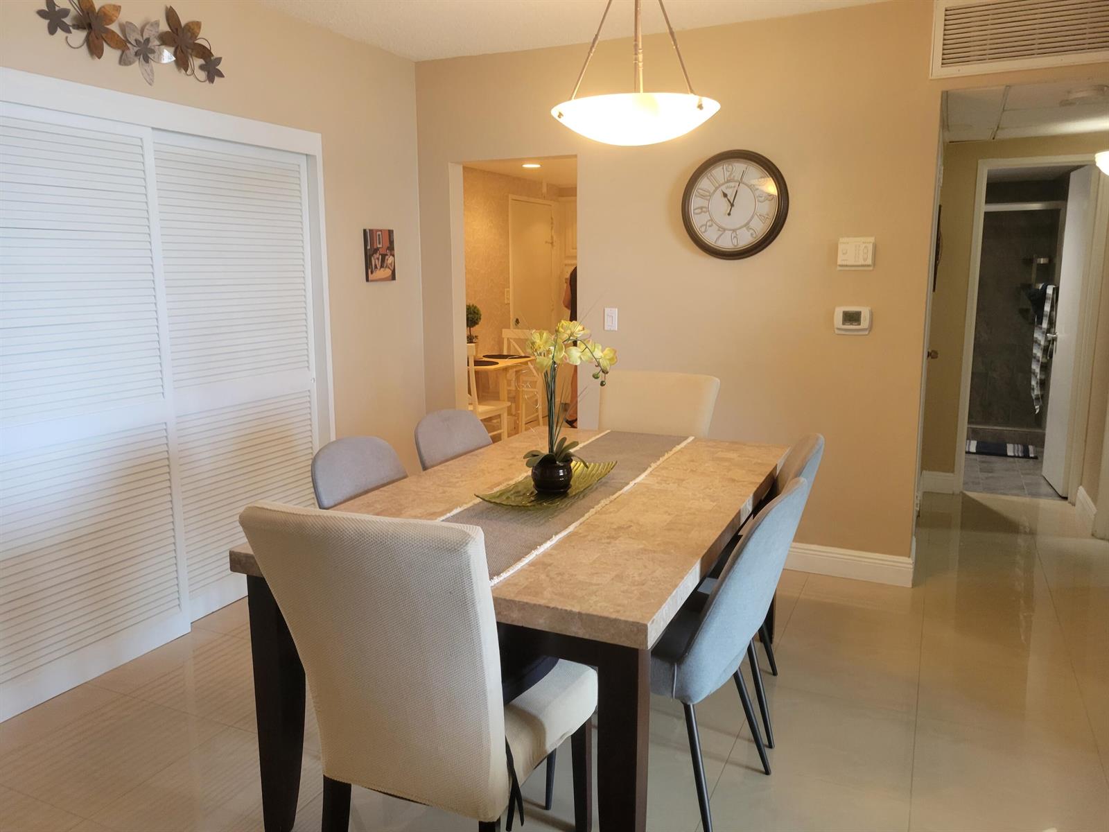 A dining room features a stone-topped table, six upholstered chairs, and a wall clock — 3901 S Ocean Drive # 12t, Hollywood FL 33019, HOLLYWOOD, FL