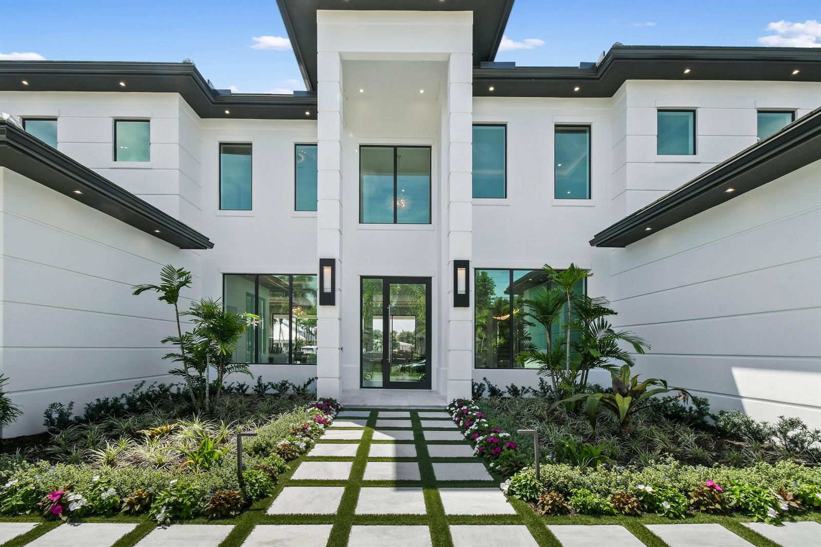 A modern white two-story house features a glass front door and a paved walkway — 2408 Azure Circle, Palm Beach Gardens FL 33410, PALM BEACH GARDENS, FL