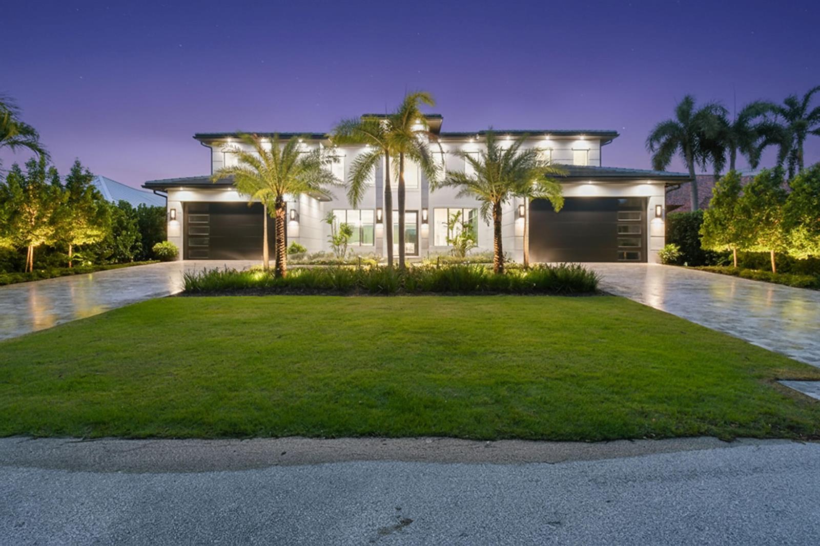 A two-story modern house with a symmetrical facade, two garages, and palm trees at dusk — 2408 Azure Circle, Palm Beach Gardens FL 33410, PALM BEACH GARDENS, FL