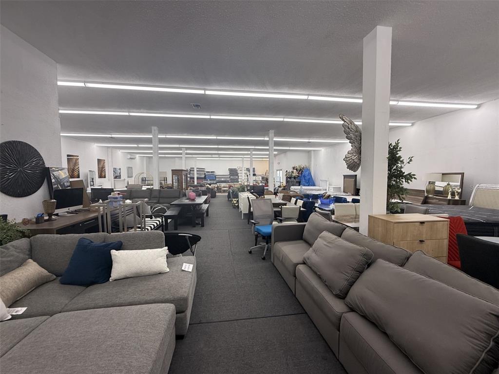 A large furniture showroom features rows of sofas, tables, and chairs on a carpeted floor — 2698 S ORANGE BLOSSOM TRAIL, ORLANDO, FL
